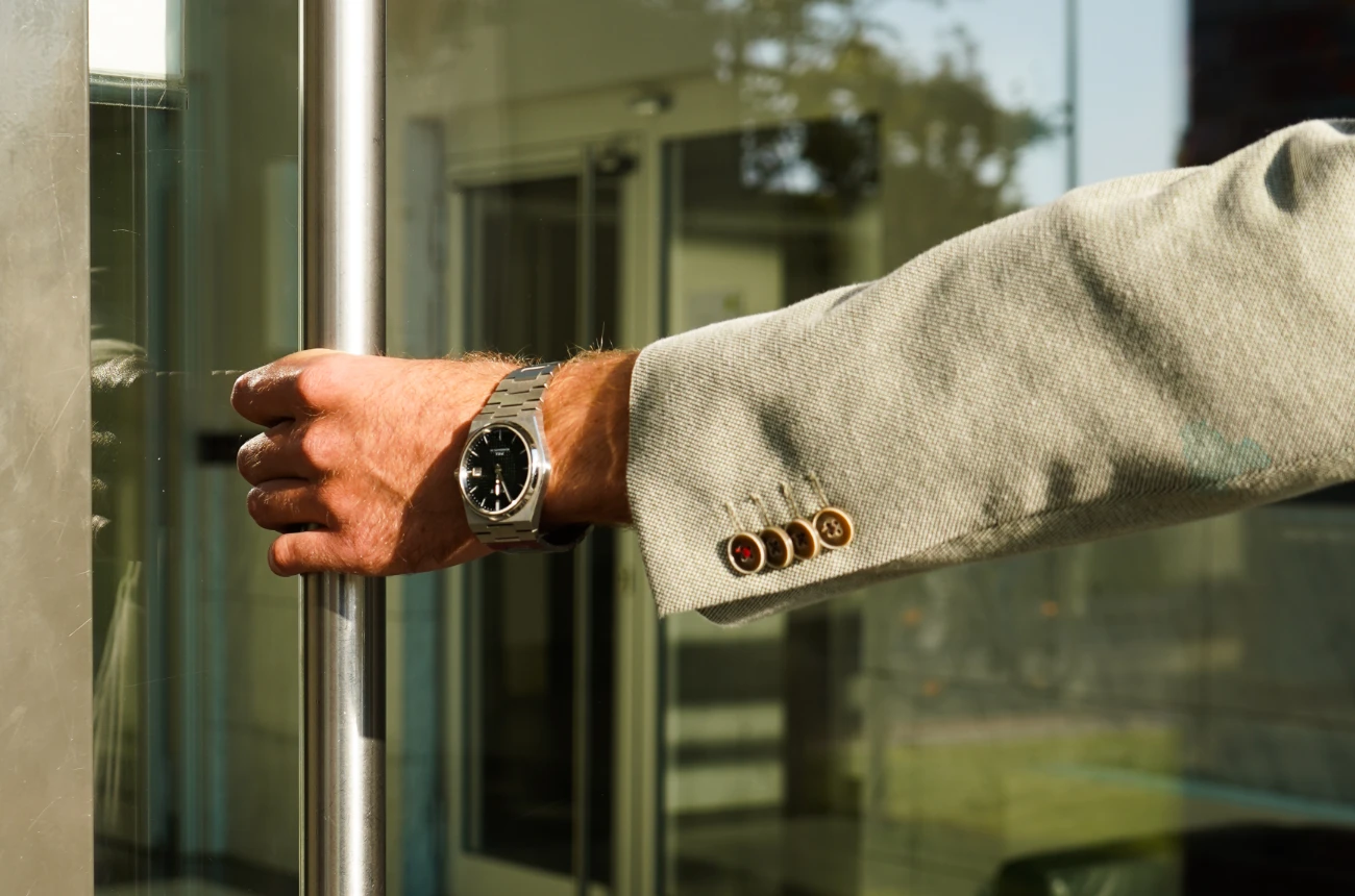 Der Arm von einem Mann in einem Anzug, der eine Tür öffnet